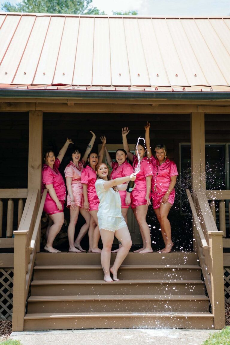 Bride and bridesmaids in pink robes celebrating with confetti on the guest house steps