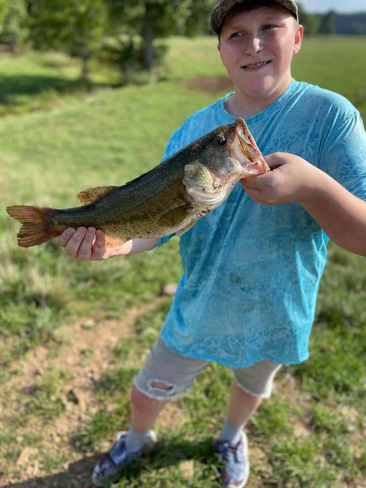 A young angler holding up a largemouth bass caught on the farm's private lake