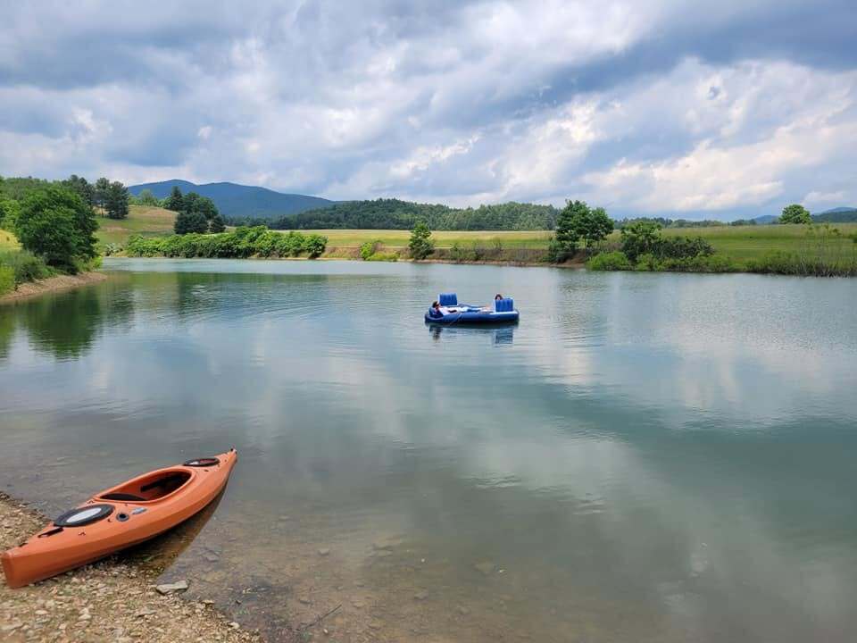 Kayak pulled up on the shore of the private lake with a paddle boat out on the water